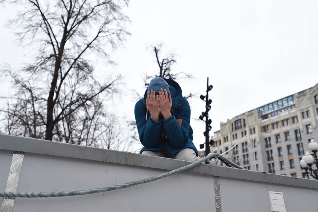 Человек закрывает лицо руками на митинге