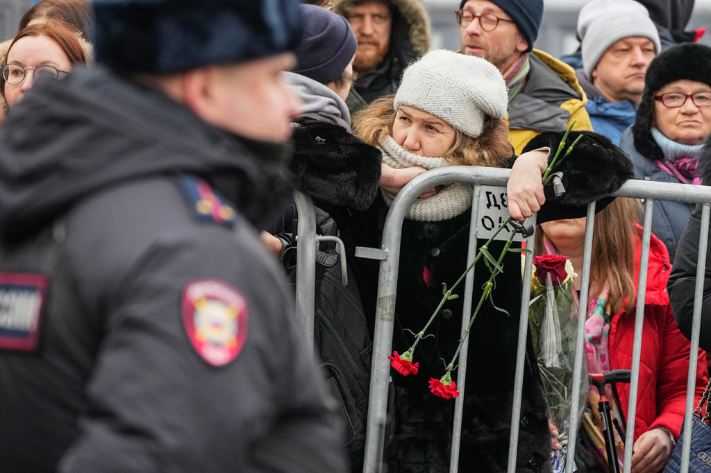 Люди за ограждениями с цветами